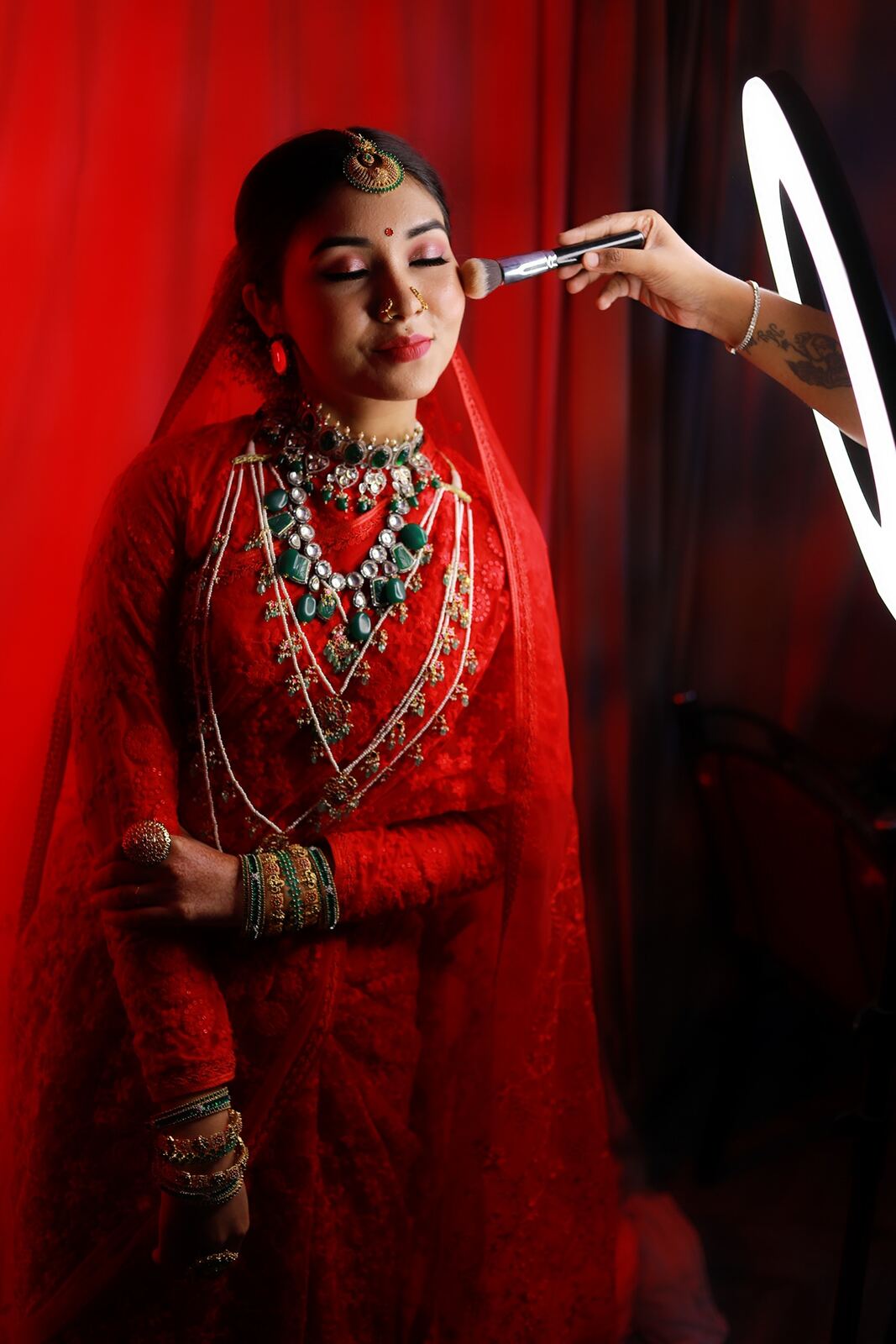 Bride in red saree getting traditional bridal makeup at Blossom Bridal Makeover, Madurai